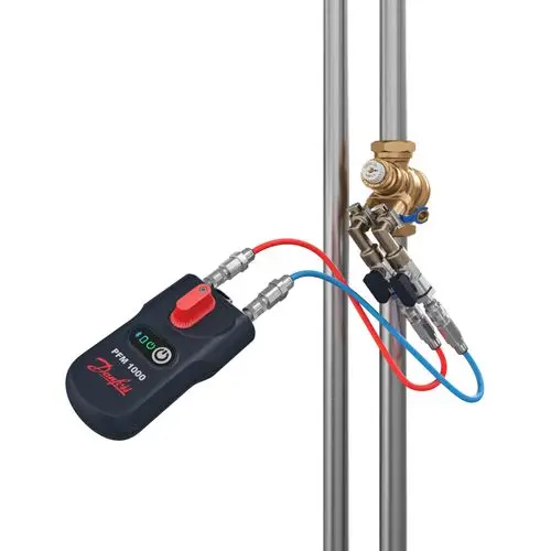 Digitales Messgerät von Danfoss mit zwei Schlauchanschlüssen, Temperatursensor und Messadapter, befestigt an einer Rohrinstallation.